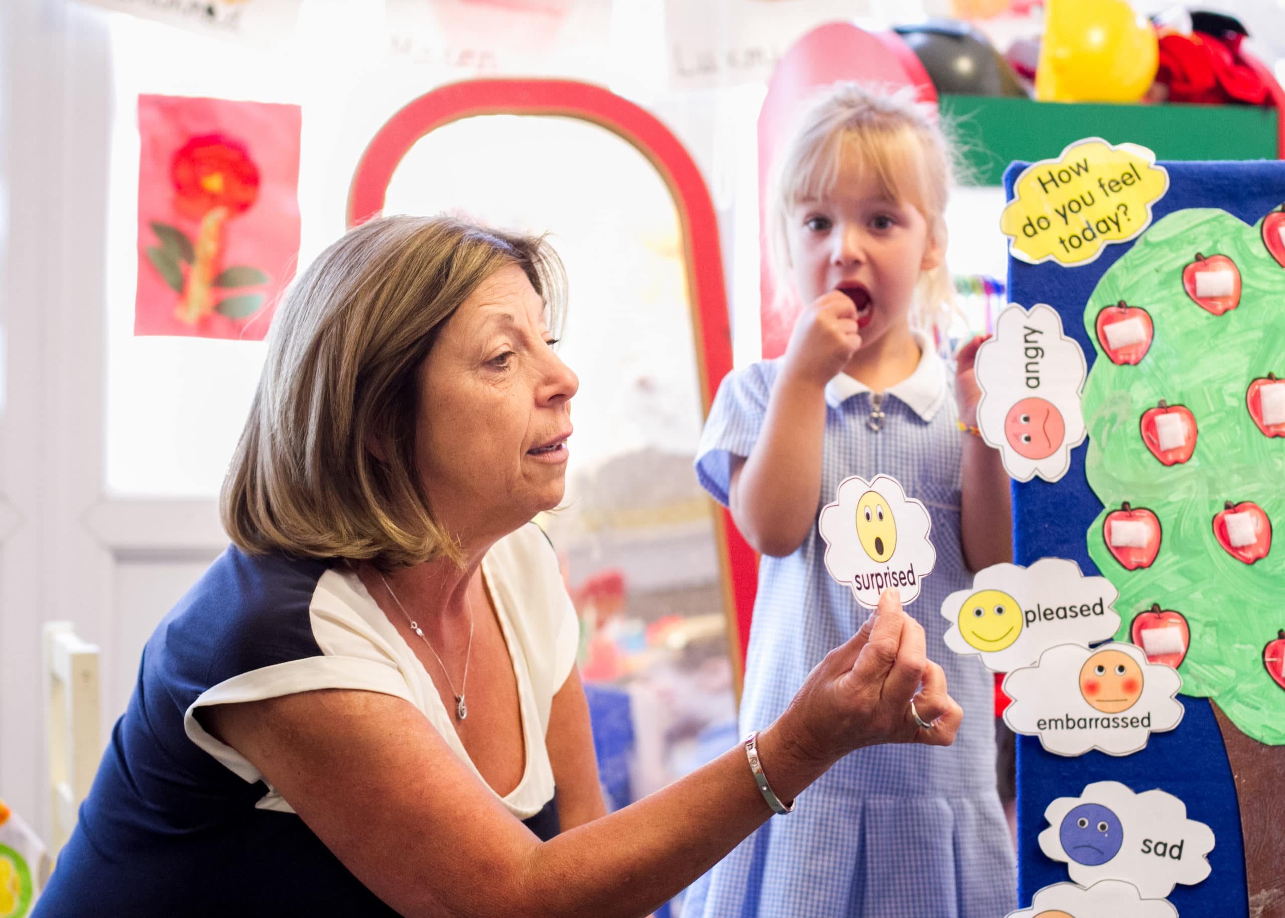 Nurture practitioner showing an emotion card titled 'surprise' with a young child by her side