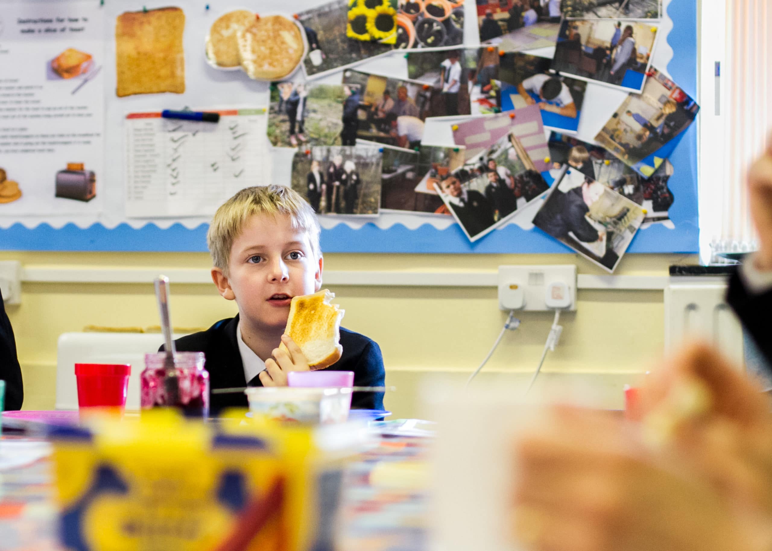 child at table at school eating toast