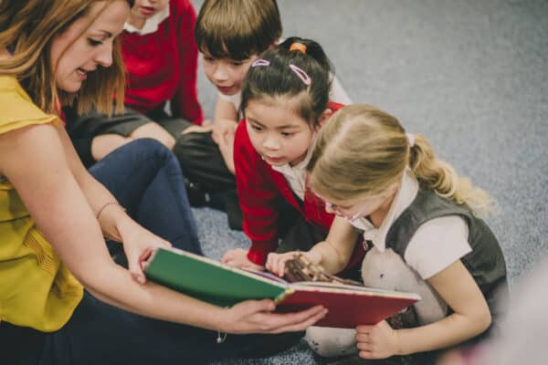 Teacher reading book to a group of primary school children